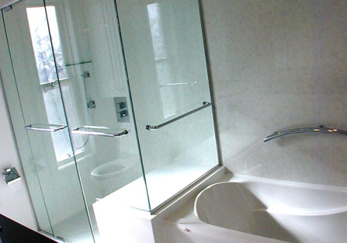 Custom glass panels on a Corian seat with shower bars and a swinging door